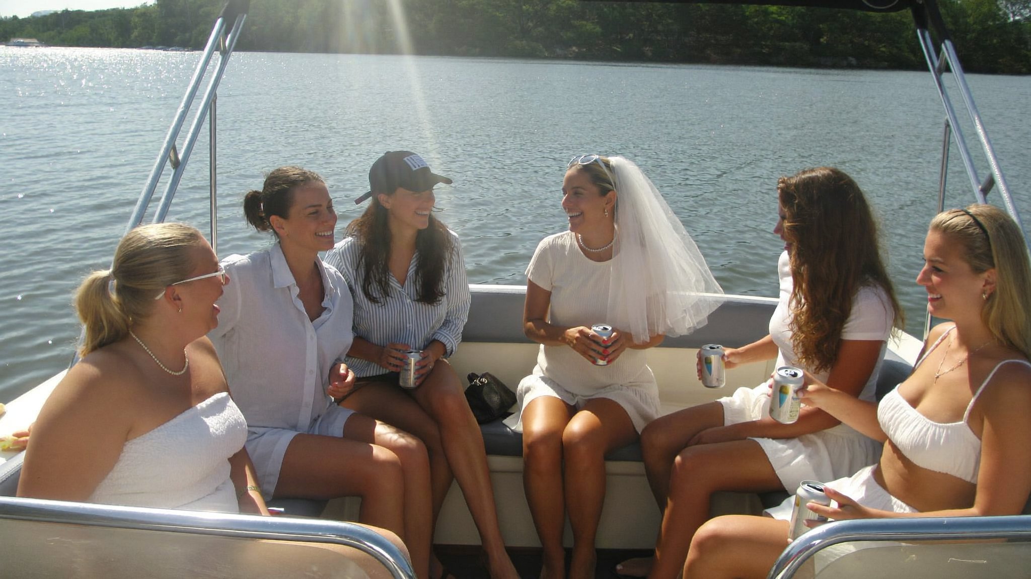 Bachelorette party laughing together on a pontoon boat on a lake near Nashville, bride wearing a veil
