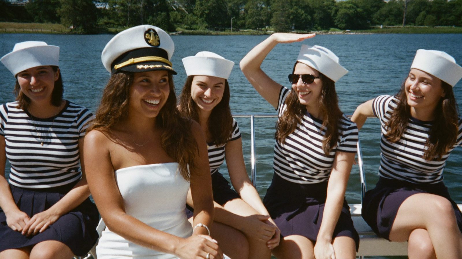 Bride in captains hat with crew in sailor stripes on a pontoon boat - Captains Crew bachelorette theme