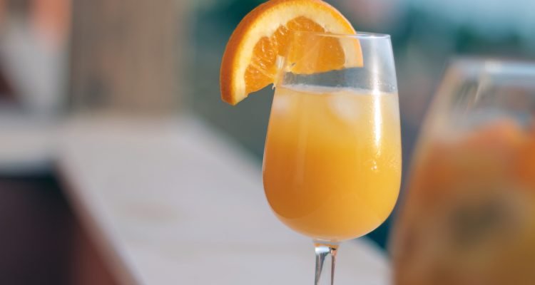 glass filled with mimosa and an orange slice